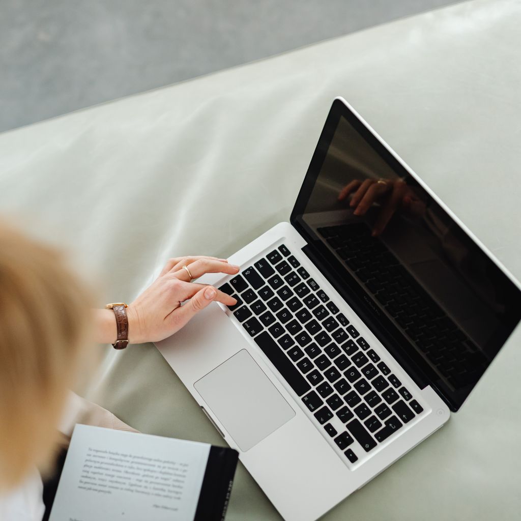 A woman browsing the web on a laptop from her sofa at home